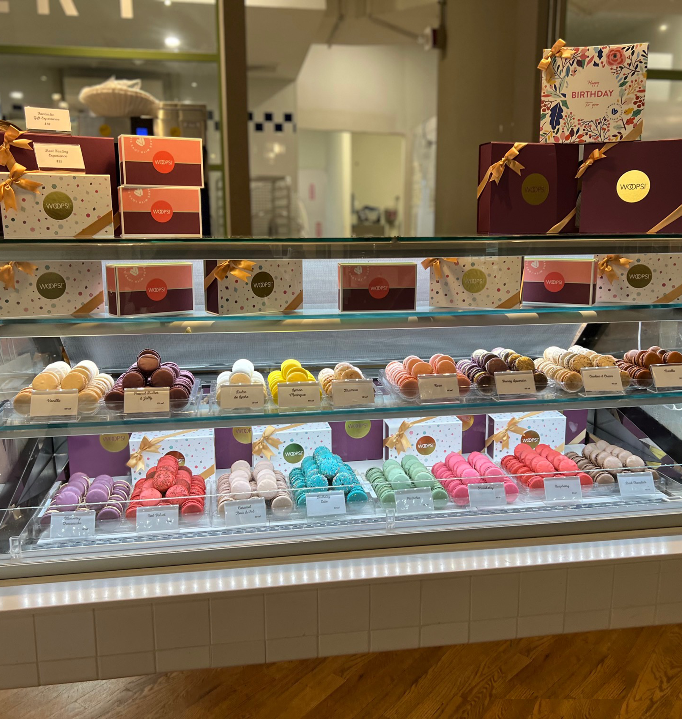 Woops! counter filled with colorful French macarons and gift boxes with ribbons