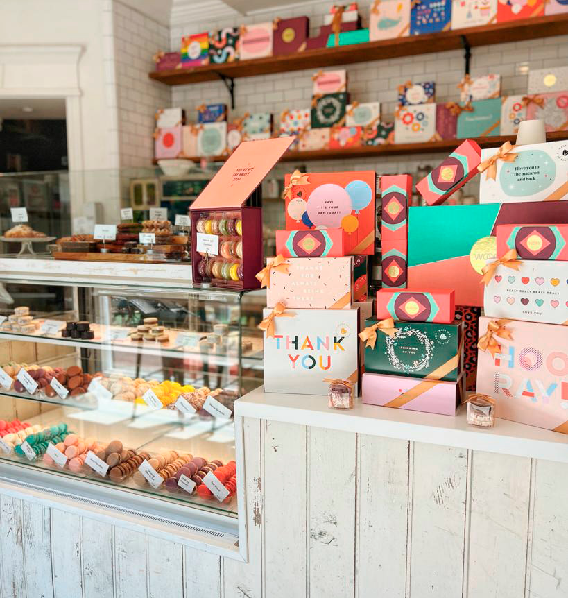 Woops! bakeshop with boxes and colorful French macarons on a counter