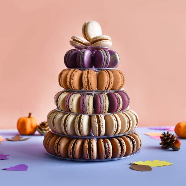 A large macaron pyramid is surrounded by pumpkins and acorns.