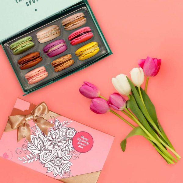 A box of 9 French macarons with assorted flavors has a box of French macarons with a Spring sleeve to its side.