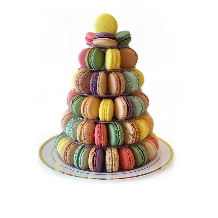 A medium-sized French macarons pyramid with assorted flavors is standing on a white and gold plate.