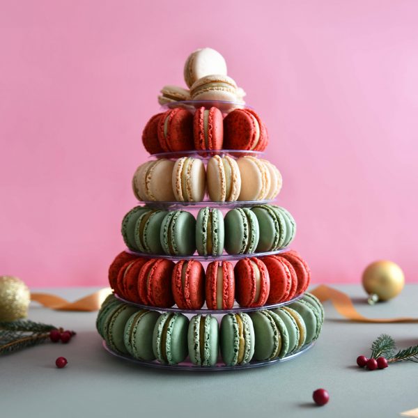 A macaron pyramid with Vanilla, Pistachio, and Red Velvet macarons is surrounded by holiday ornaments.