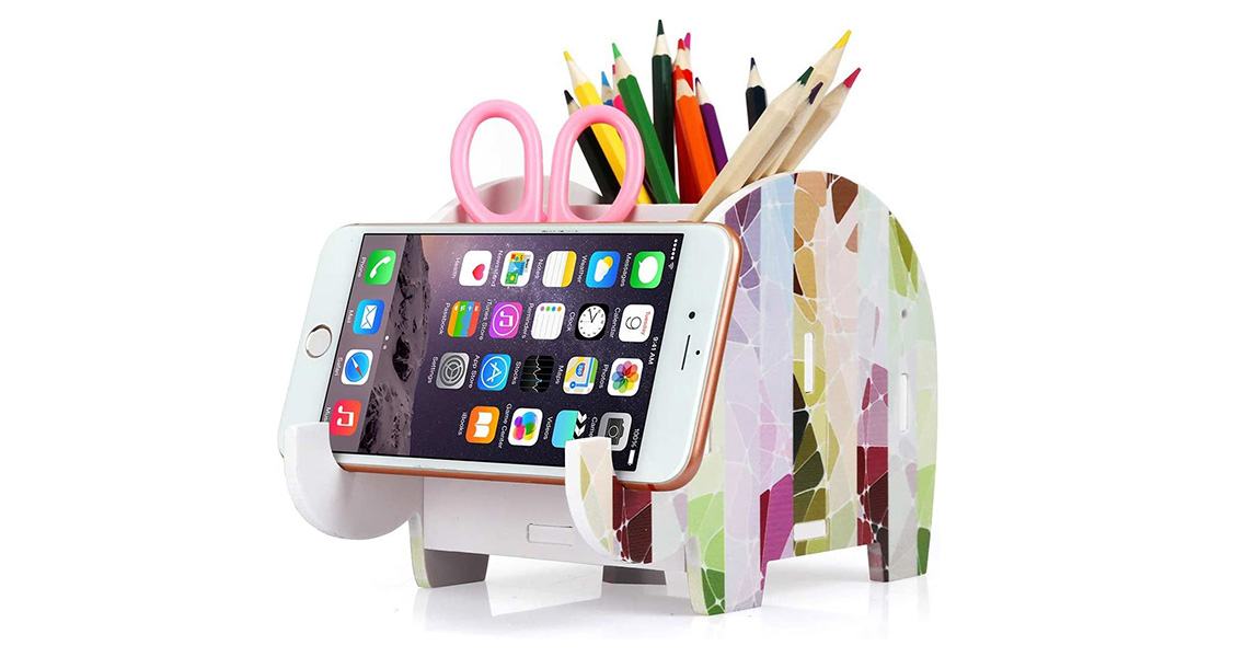 An elephant-shaped pencil stand is full of school supplies and is holding an iPhone.