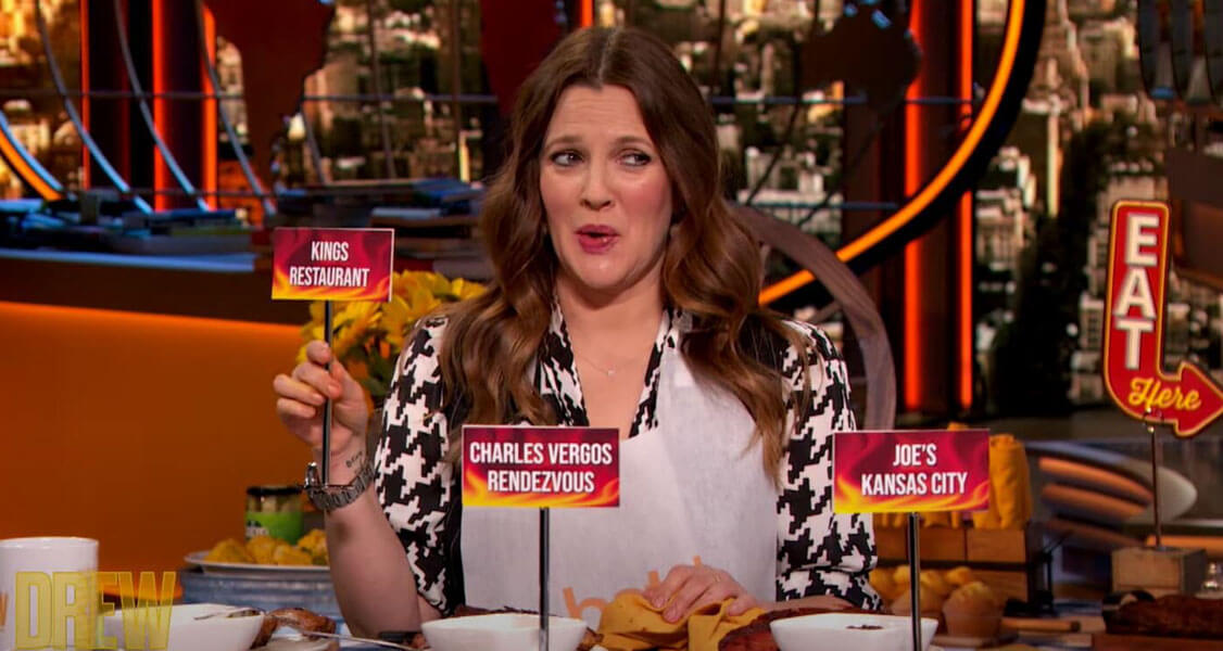 A brunette woman is holding a King’s Restaurant card in her hand. In front of her are two other fire-colored cards.