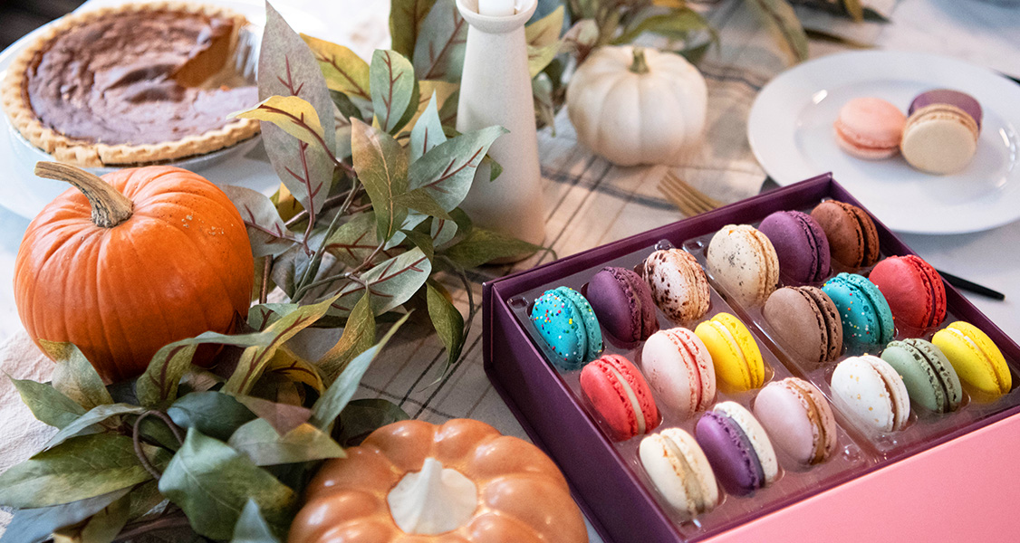 Woops! box of assorted French macarons in a Thanksgiving table with pumpkins, leaves, and a pie at the back