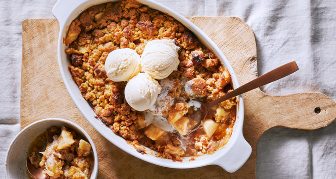 Apple crumble on a tray with Vanilla ice cream and a spoon ready to serve