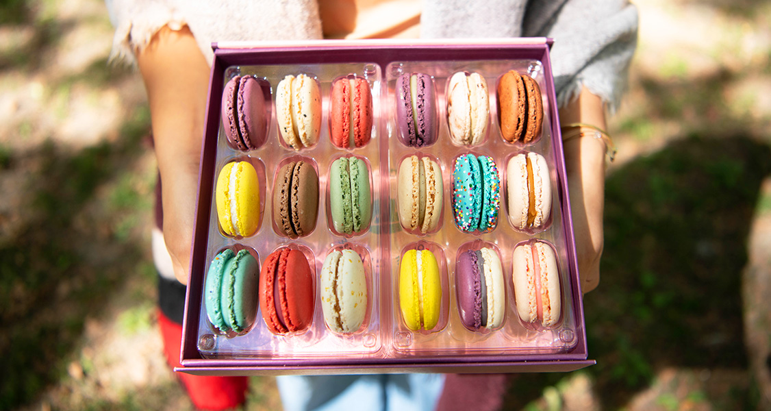 Woman holding a box of French macarons in the sun