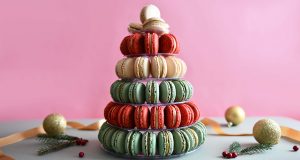 A French macaron pyramid is surrounded by holiday ornaments.