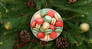 A plate full of assorted French macaron is on top of holiday ornaments.