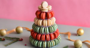 A French macaron pyramid surrounded by holiday ornaments.