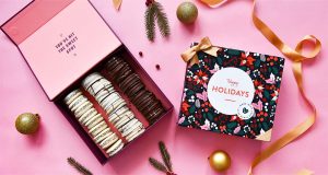 Open box of alfajores on a pink background with ribbon and Christmas decorations