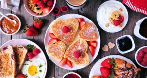 A plate full of heart-shaped pancakes is surrounded by plates full of jam, pancakes, toast, granola, and eggs. https://www.istockphoto.com/es/fotos/valentines-day-food