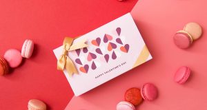  A box of macarons with a Valentine’s Day sleeve is surrounded by assorted macarons