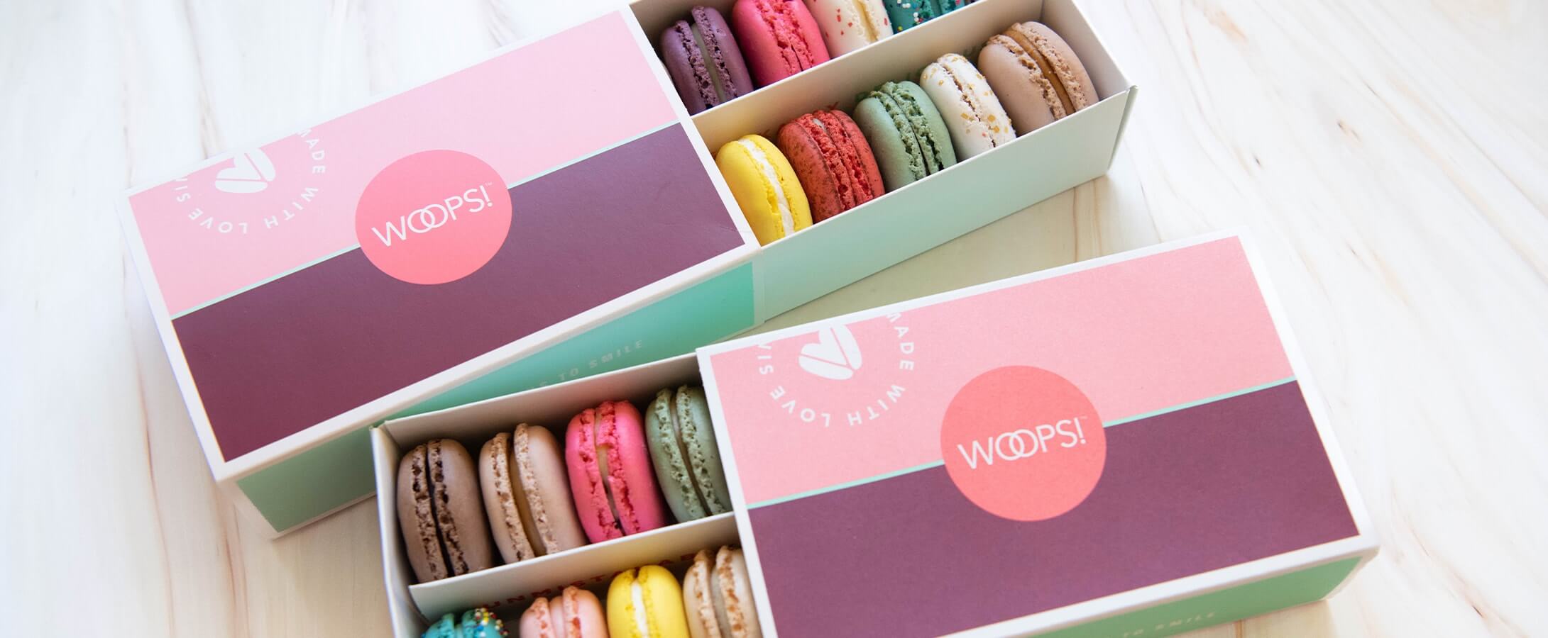 Two Woops! boxes of 12 macarons with assorted flavors.