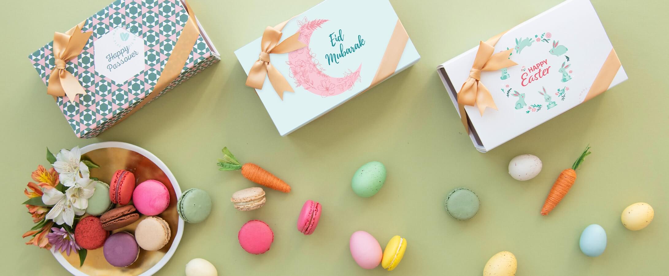 Four Woops! Macaron boxes with Eid, Passover, and Easter sleeves have a plate full of macarons and flowers plus several macarons, eggs, and carrots below.