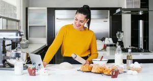 A woman in a yellow sweater is cooking. She’s surrounded by kitchen appliances