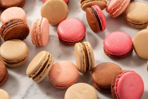 Numerous assorted French macarons are lying around