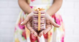 A woman is holding a favor box of two Honey Lavender macarons in her hands