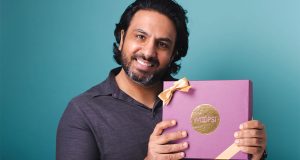  A smiling man with black hair is holding a purple Woops! Box in his hands