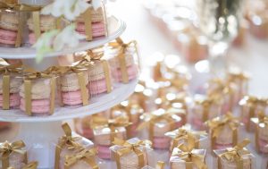 Numerous French macaron wedding favor boxes with golden ribbons.