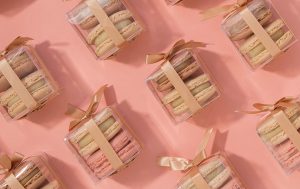 Numerous French macaron wedding favor boxes with golden ribbons.