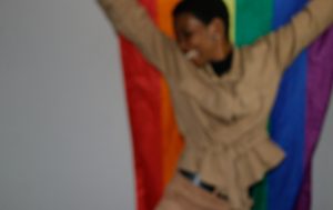 A smiling woman holding a Pride flag.