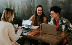 Three women laughing while working on their laptops.