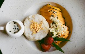 A big white plate with mango sticky rice and berries.