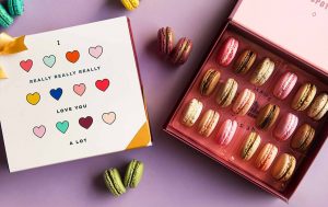 A box full of 18 assorted macarons has a macaron box with an I Love you sleeve.