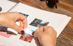 A woman is sticking a photo to a photo album.