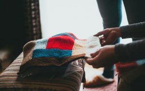 Two hands folding a colorful soft blanket.