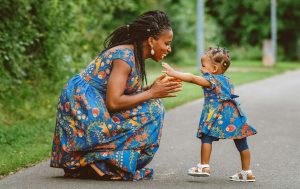 A woman kneeling down next to a little girl.