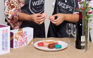 Two women holding a macaron with mother’s day boxes on the table. 
