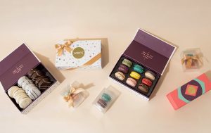 7 Woops! boxes with assorted macarons and alfajores around. 