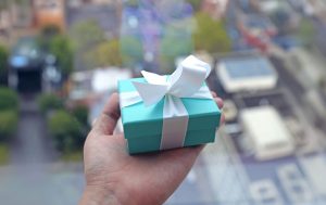 Green and white gift box in a hand.